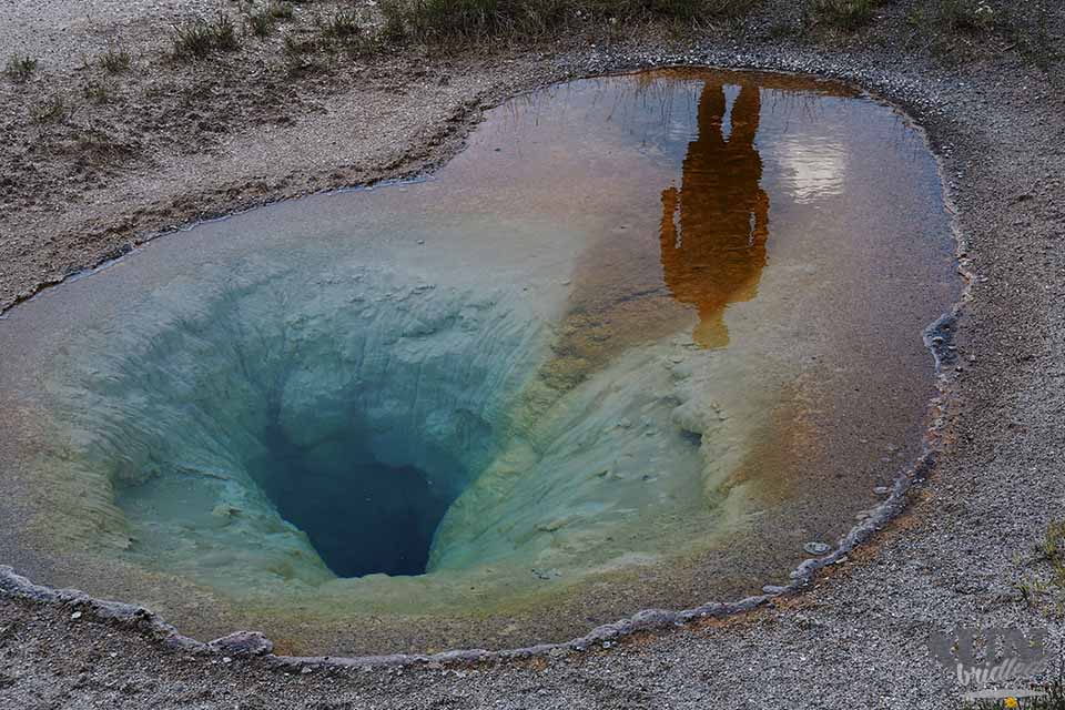 Man in the reflecting water of a hot spring in Yellowstone